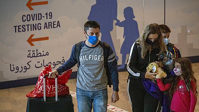 Travellers wearing protective face masks arrive at the Ben Gurion Airport near Tel Aviv, Israel, Sunday, Nov. 28, 2021.