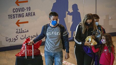 Travellers wearing protective face masks arrive at the Ben Gurion Airport near Tel Aviv, Israel, Sunday, Nov. 28, 2021. 