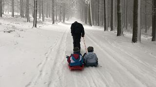 Férfi húzza maga után gyerekeit a franciaországi Loire megye egyik hegyi útján. A hétvégén jelentős mennyiségű hó esett a térségben