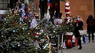 Egy nő nézelődik egy karácsonyi dekorációba öltöztetett mayfair-i borkereskedés előtt Londonban