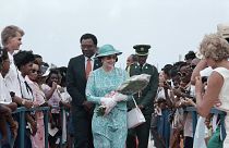 Barbadians line both sides of a red carpet as British Queen Elizabeth II carries flowers presented to her on Friday, March 10, 1989 at Queen's College in Barbados.