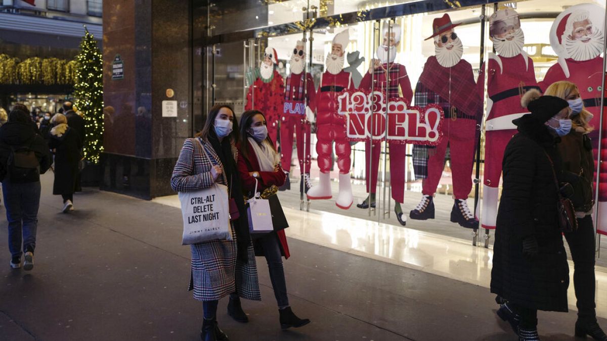 Des passants masqués dans la rue à Paris devant les vitrines de Noël, le 29/11/2021