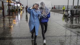 A couple shelters against a heavy rain with an umbrella during a stormy day in Istanbul.