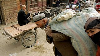Doğu Türkistan'ın Hoten kentinde yün taşıyan Uygur adam ve kadın (arşiv) 