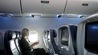 سيدة تجلس مرتدية كمامة واقية في طائرة 