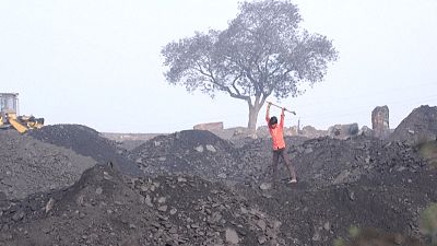 Young boy breaks coal in a coalyard