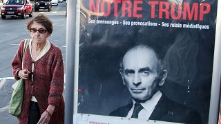 ARCHIVO - Una mujer pasa por delante de un cartel de Eric Zemmour que dice "nuestro Trump" en francés, 28/10/2021, Biarritz, Francia