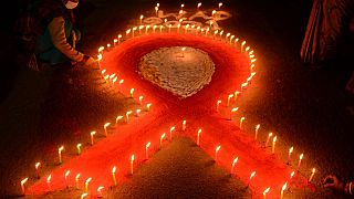 Lights candles forming the shape of a red ribbon during an awareness event organised on the eve of the 'World AIDS Day' in India