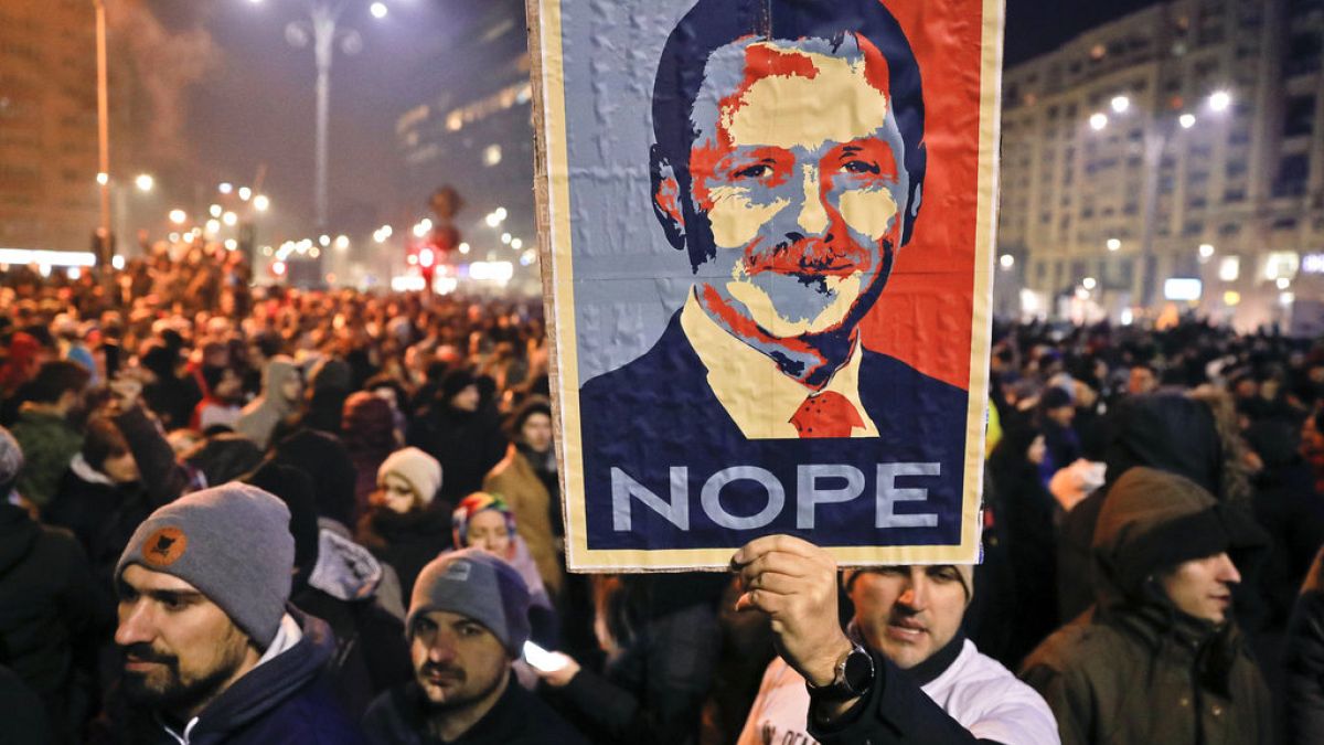 In this Tuesday, Jan. 31, 2017, file picture a man holds a poster depicting the leader of the ruling Social Democratic party Liviu Dragnea, during a protest in Bucharest.