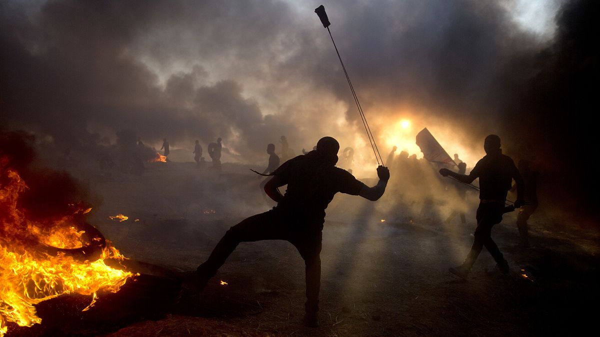 دخان أسود في السماء مع قيام متظاهرين فلسطينيين بإلقاء الحجارة على القوات الإسرائيلية خلال مظاهرة على حدود قطاع غزة مع إسرائيل
