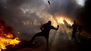 دخان أسود في السماء مع قيام متظاهرين فلسطينيين بإلقاء الحجارة على القوات الإسرائيلية خلال مظاهرة على حدود قطاع غزة مع إسرائيل