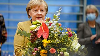 La canciller alemana Angela Merkel sostiene un ramo de flores de manos del vicecanciller y ministro de Economía Olaf Scholz, 24/11/2021, Berlín, Alemania