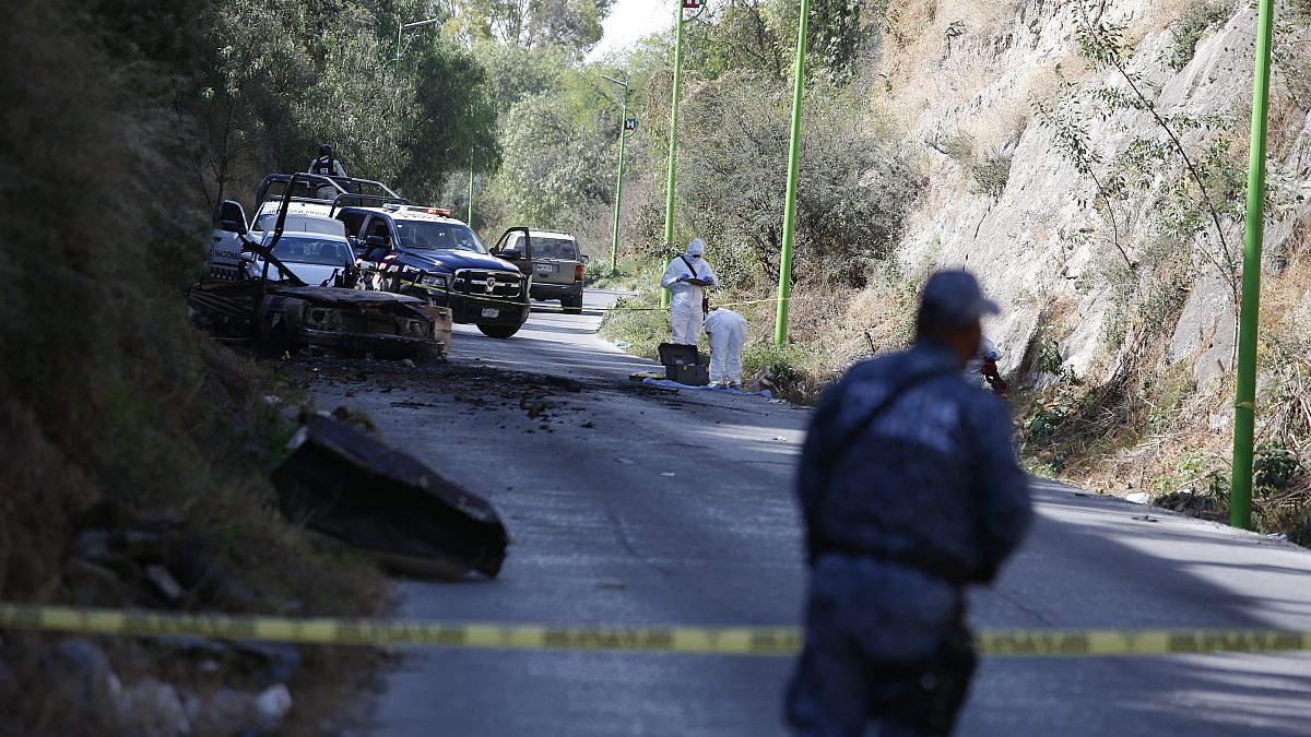 Forensic investigators work an area where a burned-out car was found after a gang rammed several vehicles into a prison and escaped with nine inmates, in Tula, Mexico.