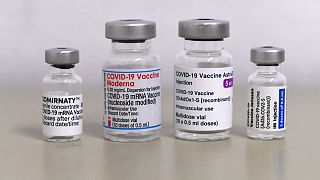 Vials of the COVID-19 vaccine by Moderna (C) and Pfizer / BioNTech against the novel coronavirus stand on a table in a vaccination center in Sonthofen, southern Germany.
