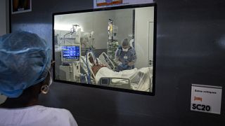 Medical staff members tend to a Covid-19 patient under respiratory assistance, in a room of the intensive care unit in Martinique.