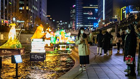 A woman poses for photos as she visits the 13th Seoul Lantern Festival in the Cheonggyecheon area of Seoul on November 26, 2021.