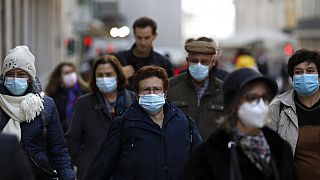 People wearing face masks to curb the spread of COVID-19 walk in downtown Lisbon, Monday, Nov. 29, 2021. 
