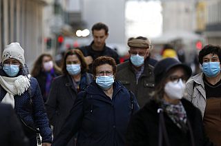 People wearing face masks to curb the spread of COVID-19 walk in downtown Lisbon, Monday, Nov. 29, 2021.