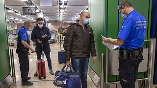 Zwei Grenzbeamte lassen sich am Flughafen Genf von Reisenden die Papiere zeigen (Aufnahmen vom Februar 2021)
