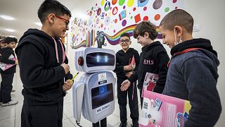 Palestinian students interact with a locally-made educational robot during a science class at a private school in Gaza City