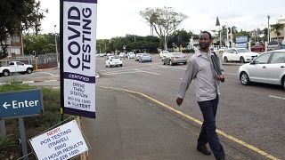 A man walks past a mobile COVID-19 testing station in Durban, South Africa, Friday, Dec. 3 2021. The new omicron variant appears to be driving a dramatic surge in the country.