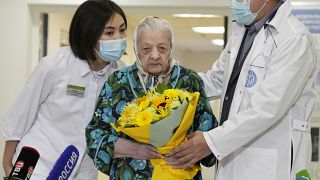 Doctors greet 101-year-old patient Pelageya Poyarkova with flowers as she leaves a COVID recovery ward, Federal Center for Brain and Neurotechnology, Moscow, Dec. 3, 2021.