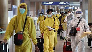 Védőruhát viselő utasok érkeznek a szöuli Incshon nemzetközi repülőtéren