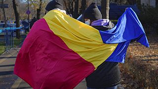 Román zászlóval sétál egy pár Bukarestben 2021. december 1.én