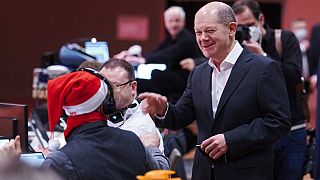 Olaf Scholz (SPD), Chancellor-designate, greets a party member wearing a Santa Claus hat at the Berlin SPD state party conference, in Berlin, Sunday, Dec. 5, 2021.
