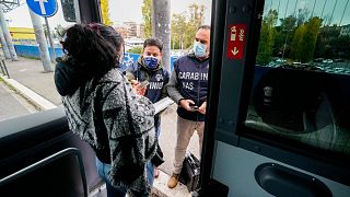 Carabinieri policemen check the green health pass of public transportation passengers in Rome, Monday, Dec. 6, 2021