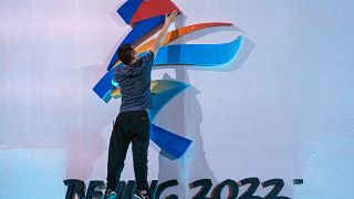 A crew member fixes a logo for the 2022 Beijing Winter Olympics before a launch ceremony.