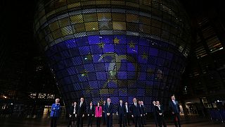 A presidente do BCE, Christine Lagarde, e os ministros das Finanças da Zona Euro em frente a um painel que assinala os 20 anos do Euro