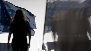 Une femme marche vers des drapeaux de l'Union européenne à Bruxelles.