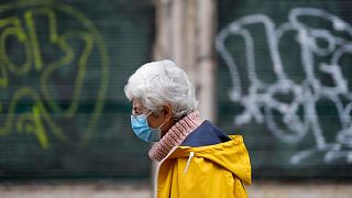 A woman wearing a face mask walks in downtown Lisbon, Monday, Dec. 6, 2021.