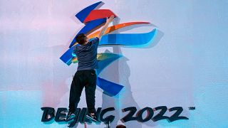 أحد العاملين الصينيين يثبت شعار دورة الألعاب الأولمبية الشتوية في بكين لعام 2022 قبل الافتتاح الرسمي المقرر في الرابع من شهر شباط/فبراير