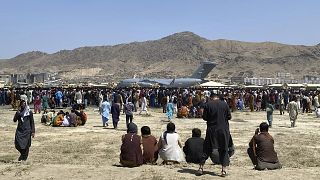 Hundreds of people gathered at the perimeter of Kabul international airport in August.