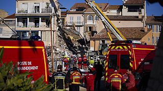 Firemen stand at a three-story apartment building after it collapsed in a suspected gas explosion on southern France's Mediterranean coast.
