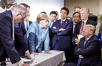 FILE - Former German Chancellor Angela Merkel, speaks with U.S. President Donald Trump, seated at right, at G7 Summit in La Malbaie, Quebec, Canada, June 9, 2018. 