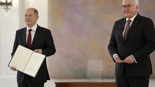 New elected German Chancellor Olaf Scholz, left, holds his letter of appointment after he received it by German President Frank-Walter Steinmeier
