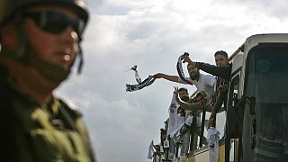 جندي إسرائيلي يشاهد أسرى فلسطينيين أطلق سراحهم يحتفلون بعد عبورهم حاجز بيتونيا العسكري إلى مدينة رام الله بالضفة الغربية، الإثنين 15 ديسمبر 2008