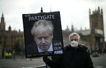 An anti-Conservative Party protester holds a placard with an image of British PM Boris Johnson including the words "Partygate" in London, Wednesday, Dec. 8, 2021.
