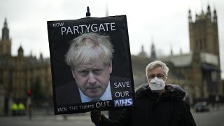 أحد المتظاهرين المناهضين لحزب المحافظين يحمل لافتة عليها صورة رئيس الوزراء البريطاني بوريس جونسون، لندن، الأربعاء، 8 ديسمبر 2021.