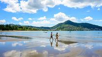 Tourists walk on a beach on the Thai island of Phuket on November 1, 2021, as Thailand welcomes the first group of tourists fully vaccinated against the Covid-19 coronavirus.