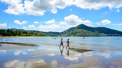 Tourists walk on a beach on the Thai island of Phuket on November 1, 2021, as Thailand welcomes the first group of tourists fully vaccinated against the Covid-19 coronavirus.