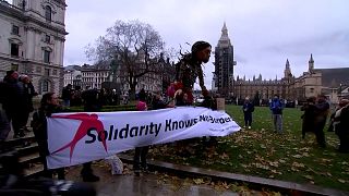 Giant puppet called Little Amal posing with members of NGO holding banner that reads: ''Solidarity knows no borders" near the Parliament Square in London.