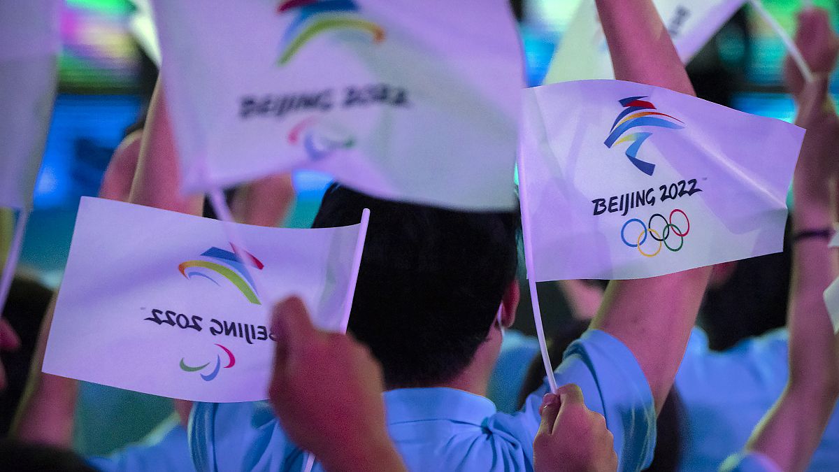 مشاركون يلوحون بالأعلام التي تحمل شعارات أولمبياد بكين الشتوية والألعاب الأولمبية للمعاقين 2022. 2021/09/17