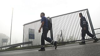 FILE: Two men walk past a section of the fence along the border between Croatia and Bosnia near the village of Maljevac, Croatia, Tuesday June 11, 2019.