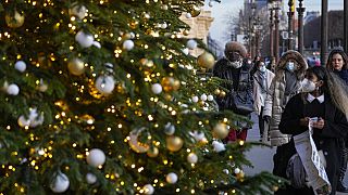 Des personnes masquées regardant les décorations de Noël dans les rues de Paris 