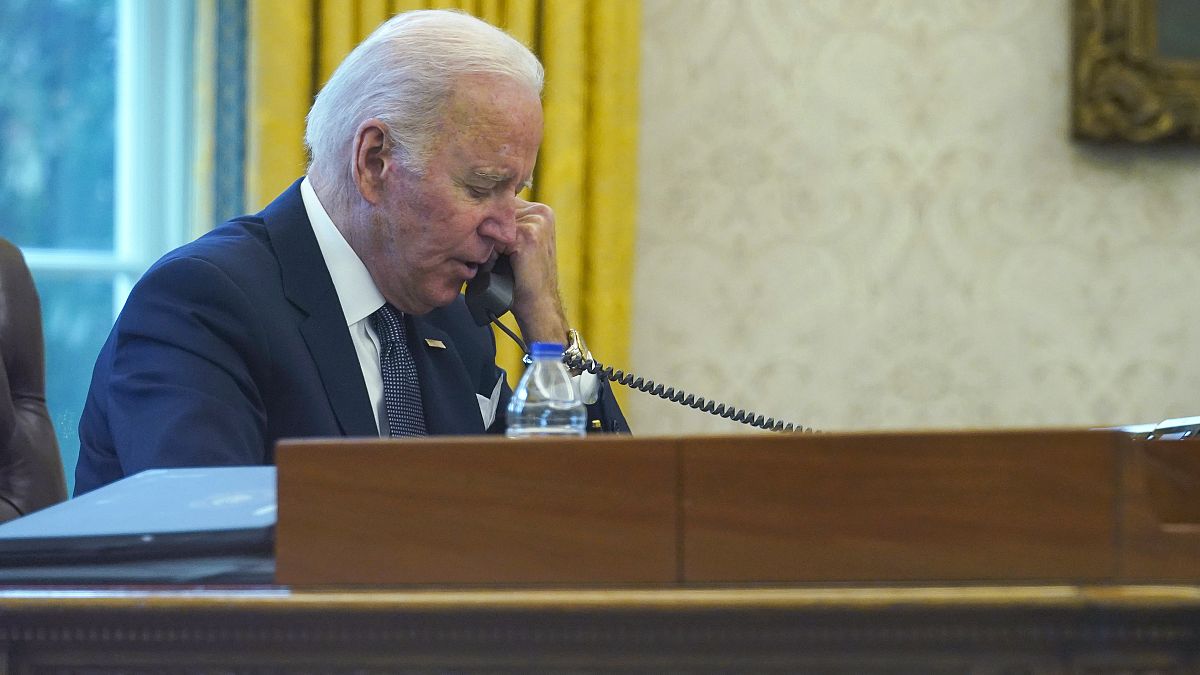 In this image made through a window, President Joe Biden talks on the phone with Ukrainian President Volodymyr Zelenskyy from the Oval Office