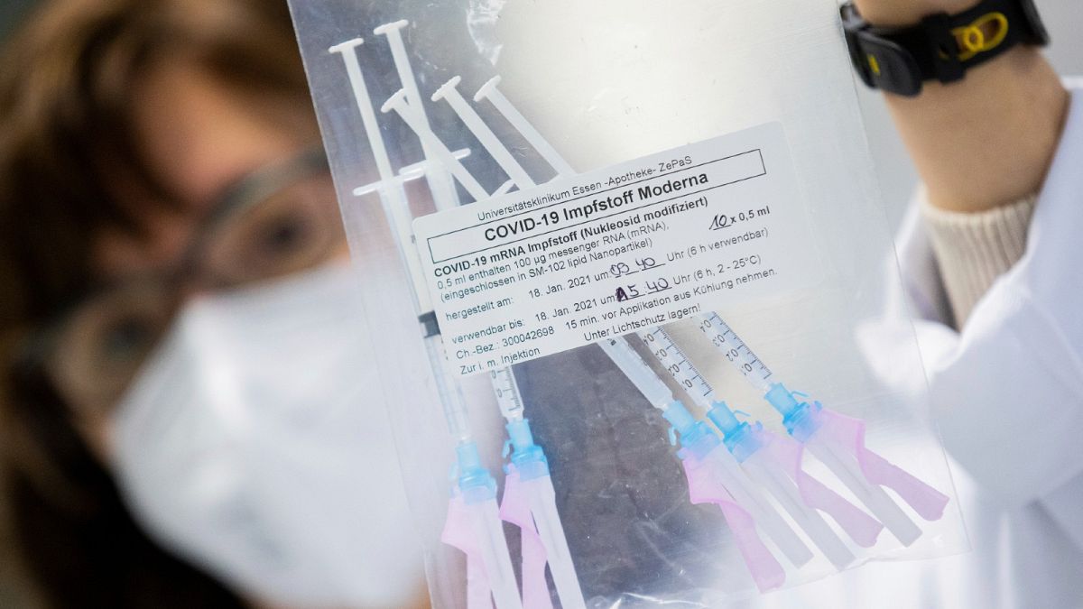 A healthcare worker shows a bag of syringes containing the Moderna new coronavirus vaccine immediately before a vaccination at the University Hospital in Essen, Germany